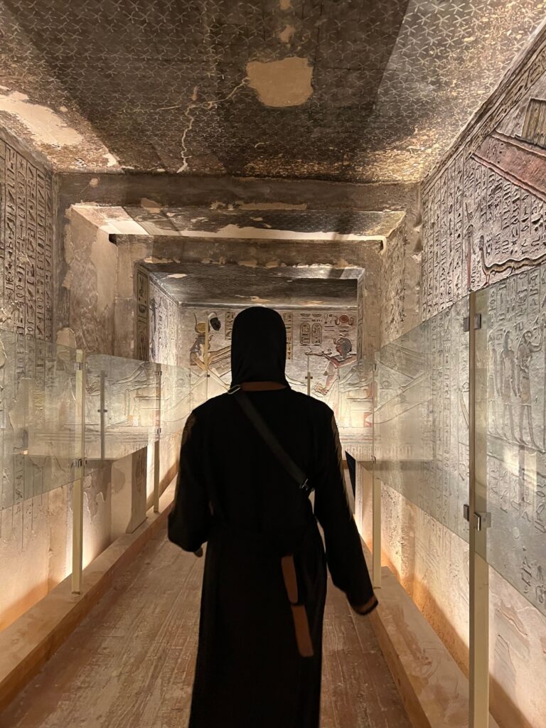 woman walking through temple of valley of the kings surrounded by hieroglyphs 