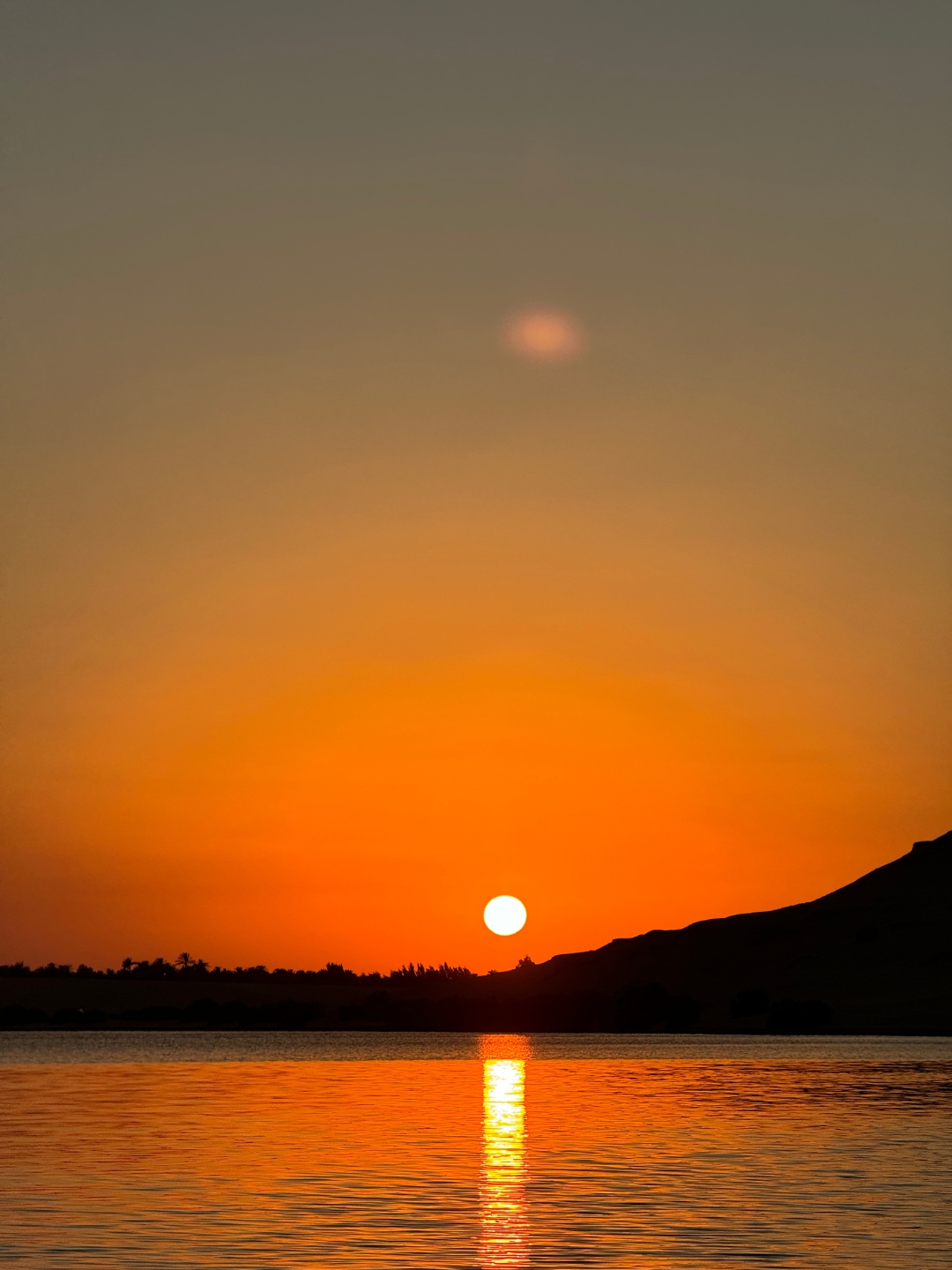 Sunset at the Magic Lake, Egypt with orange and red colors and the water reflecting the sun
