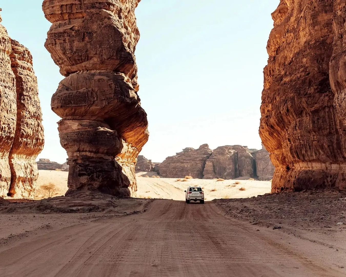 4x4 vehicle driving through rock formations in AlUla desert