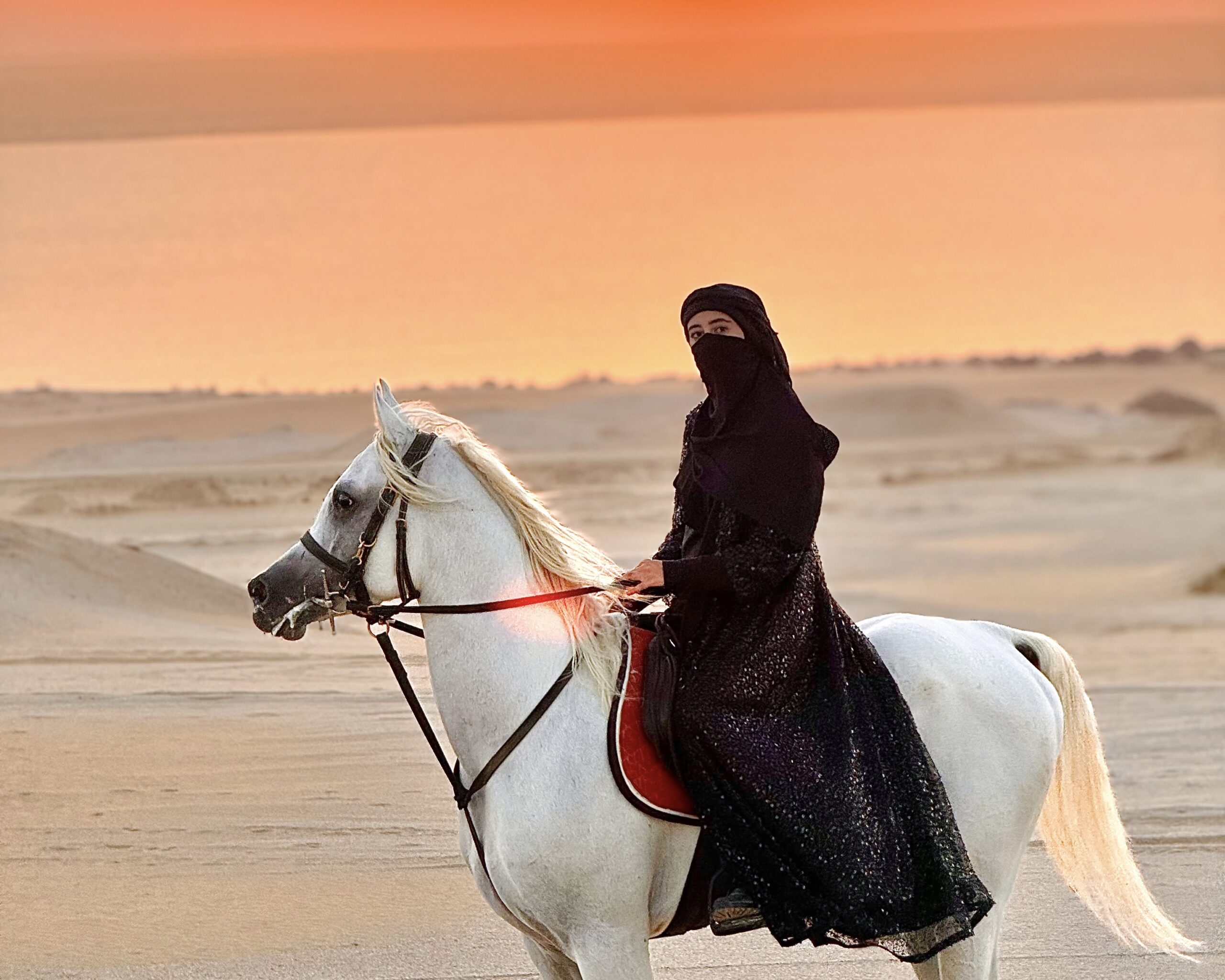 Rahma Bekhit riding a horse through the Fayoum desert at sunset, wearing a traditional abaya — representing Inside Middle East’s authentic travel and cultural storytelling.